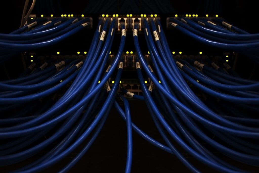 Blue network cables connected to illuminated server rack ports